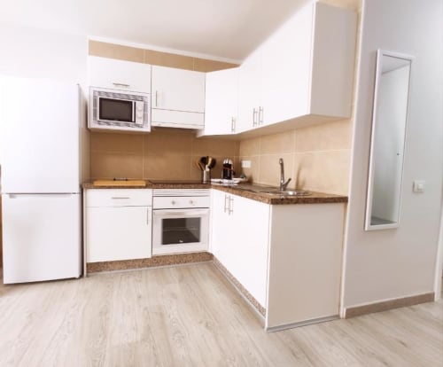 Modern kitchen with white cabinets, granite counters, and stainless steel appliances at Manage Home Tenerife apartment