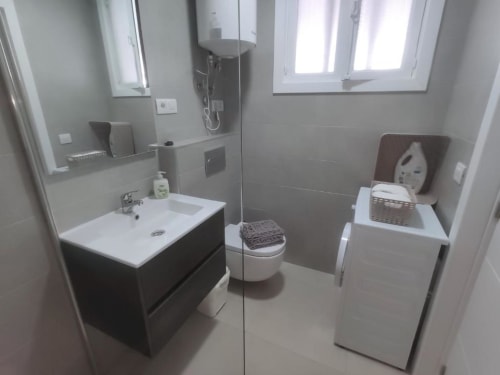 Modern bathroom in Manage Home Tenerife apartment, Playa de las Américas, featuring black vanity, white toilet, and glass