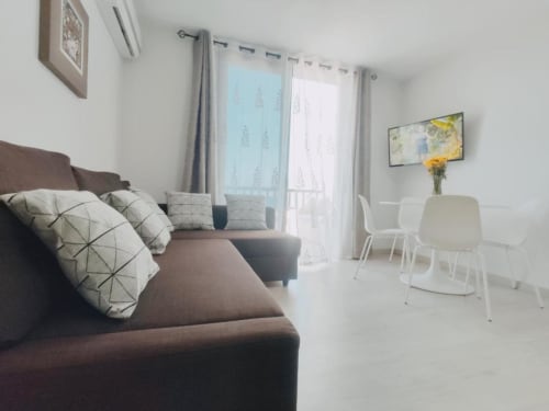 Modern apartment living room with brown sofa, sea view balcony, and contemporary furnishings in Playa de las Américas