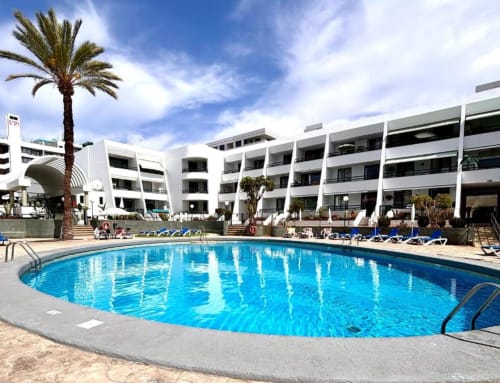 Bright blue swimming pool at Manage Home Tenerife apartments in Arona with white buildings and palm tree