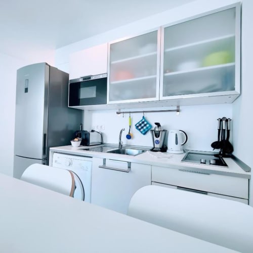 Modern white kitchen in Manage Home Tenerife apartment, Arona with stainless appliances and glass cabinets