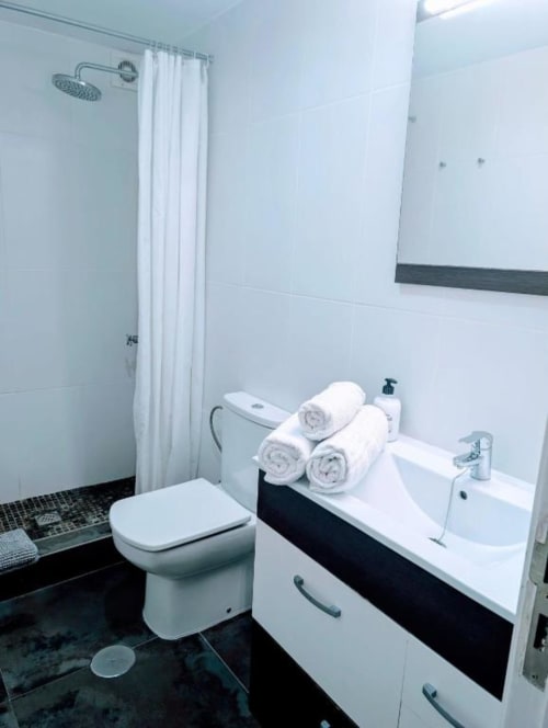 Modern bathroom at Manage Home Tenerife apartment in Arona with white sink, toilet, rolled towels, and shower