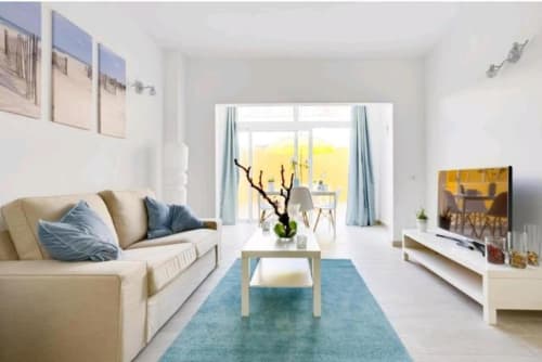 Modern apartment living room in Los Cristianos with cream sofa, blue accents, and bright patio doors opening to terrace