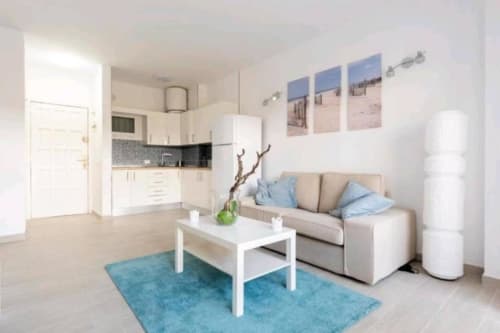 Modern apartment living room with beige sofa, white coffee table, and blue accents in Los Cristianos, Tenerife