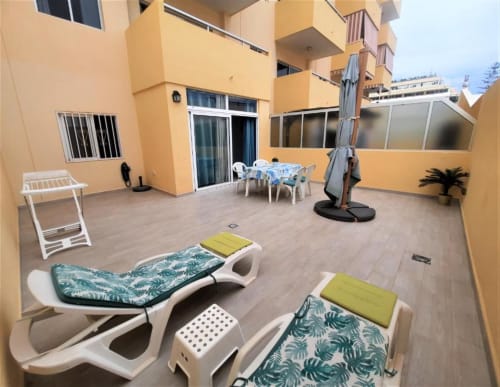 Spacious terrace at Manage Home Tenerife apartment in Los Cristianos with loungers, dining area, and ocean view