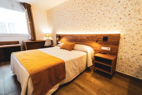 Habitación doble con cama de matrimonio, cabecero de madera y papel tapiz floral en el hotel Hospedería Angel, Huelva, España