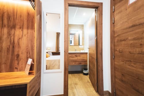 Moderno cuarto de baño con acabados de madera, lavabo y espejo en el hotel Hospedería Angel de Huelma, Jaén