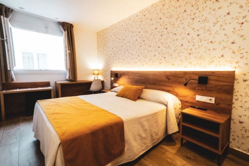 Habitación doble con cabecero de madera en Hospedería Angel de Huelma, con papel tapiz floral e iluminación cálida