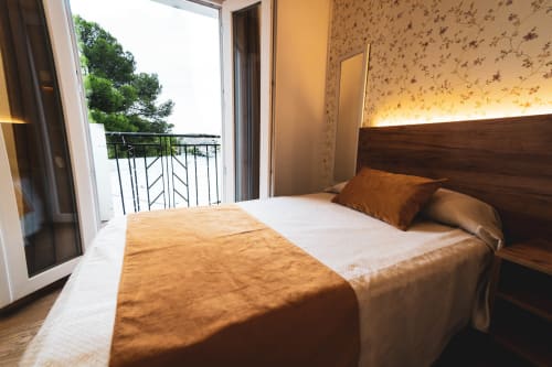 Habitación doble en Hospedería Angel de Huelma con balcón, cama de madera e iluminación cálida