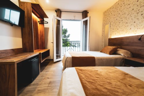 Hospedería Angel habitación doble en Huelma con dos camas, muebles de madera, balcón con vista a la ciudad, TV y escritorio