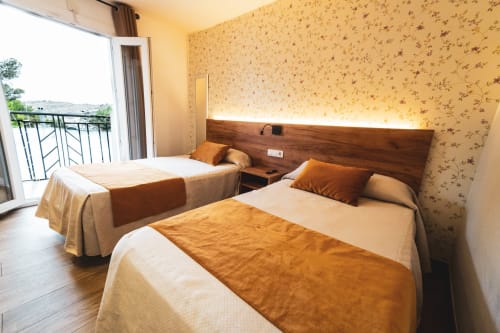 Habitación doble en Hospedería Angel Huelma con vistas desde balcón, papel tapiz floral cálido y cabecero de madera