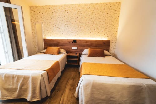Habitación doble en Hospedería Angel con cabecero de madera, detalles naranjas y vistas a la ciudad en Huelma, Jaén
