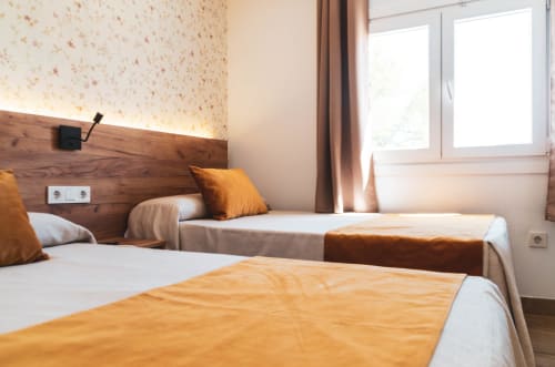 Habitación doble con dos camas, detalles en naranja y vista a la ciudad en Hospedería Angel, Huelva