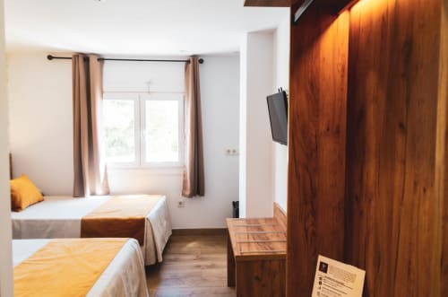 Luminosa habitación doble en Hospedería Angel de Huelma con dos camas, armario de madera y ventana con vista a la calle