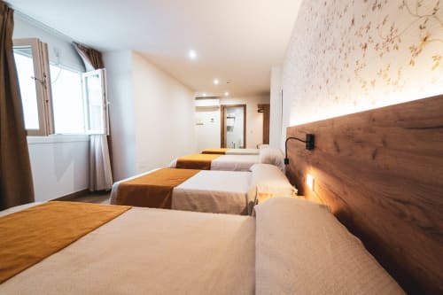 Habitación cuádruple superior de Hospedería Angel en Huelma con cuatro camas, cabeceros de madera y equipamientos modernos
