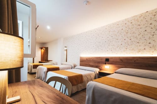 Amplia habitación Superior Cuádruple en Hospedería Angel de Huelma con múltiples camas, iluminación cálida y comodidades modernas