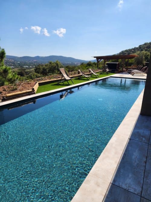 Piscine à débordement luxueuse avec transats offrant une vue panoramique sur les montagnes de Pinarellu à Les Villas d'A Storia en Corse
