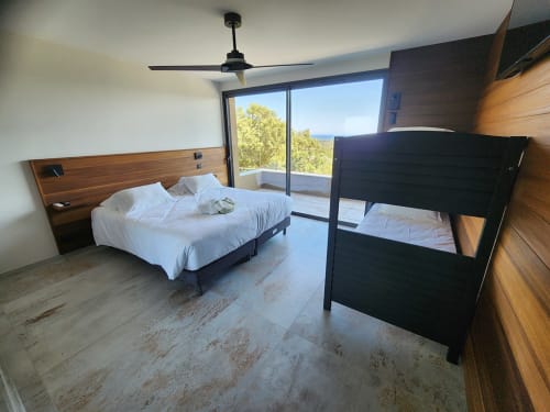 Chambre moderne à la Villa Aria Terra avec lit queen, lit superposé, vue sur la mer depuis le balcon, ventilateur de plafond et finitions en bois