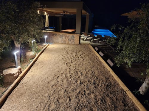 Terrain de bocce éclairé aux Villas d'A Storia à Pinarellu, avec transats et piscine visibles la nuit