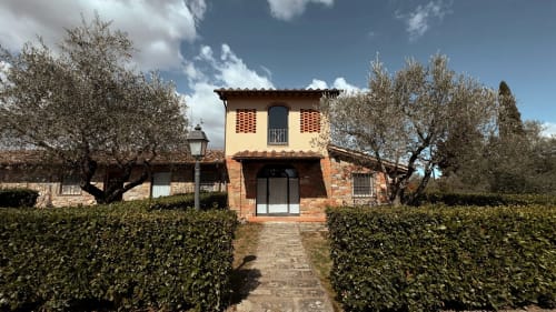 Villa in laterizio toscana a Borgo di Erboli con piano superiore giallo, circondata da oliveti e siepi curate a Cavriglia
