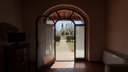 Passaggio ad arco che si apre su un giardino toscano a Borgo di Erboli, appartamento a Cavriglia con cipressi e paesaggistica curata