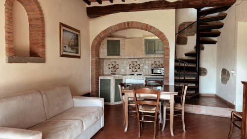 Appartamento rustico toscano a Borgo di Erboli con archi in laterizio, pavimenti in cotto, zona pranzo e divano color crema