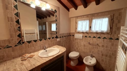 Bagno luminoso nell'appartamento Cosimo a Borgo di Erboli, Cavriglia, con doppio lavabo, toilette, bidet e piastrelle decorative