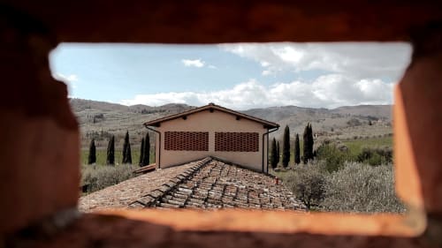 Villa toscana Borgo di Erboli attraverso un arco, con colline ondulate e cipressi a Cavriglia, Italia