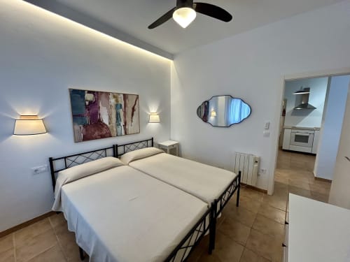 Dormitorio moderno en apartamento Judería3 de CozyHomeSevilla con cama doble, ventilador de techo, apliques de pared y acceso a cocina