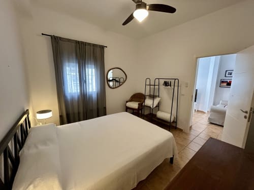 Dormitorio luminoso con cama blanca, ventilador de techo y mobiliario en el apartamento Judería3 de CozyHomeSevilla en Sevilla