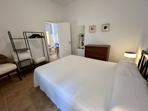 Espacioso dormitorio en apartamento Judería3 de CozyHomeSevilla con camas blancas, cómoda de madera y perchero en Sevilla