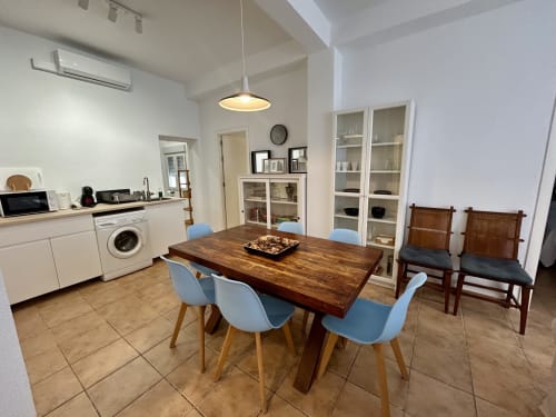 Amplia zona de cocina-comedor en el apartamento Judería3, Sevilla con mesa de madera, sillas azules y mobiliario blanco