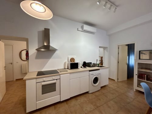 Cocina moderna en el apartamento Judería3 de Sevilla con muebles blancos, electrodomésticos de acero inoxidable e isla central
