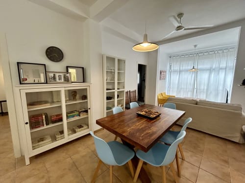 Comedor moderno en apartamento Judería3, Sevilla con mesa de madera, sillas azul claro, muebles blancos y ventilador de techo