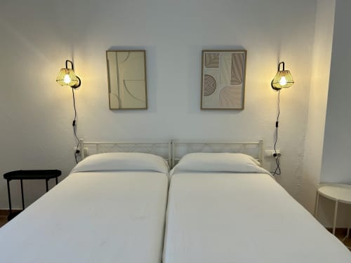 Dormitorio moderno con dos camas blancas, lámparas colgantes y arte abstracto en apartamento CozyHomeSevilla, Judería de Sevilla