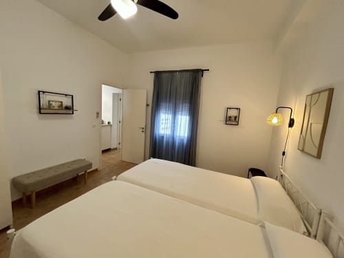 Dormitorio espacioso con dos camas individuales, ventilador de techo y comodidades modernas en el apartamento Judería3 de Sevilla