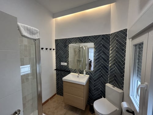 Baño moderno en apartamento CozyHomeSevilla Judería3 con pared de azulejos en espiga negra, lavamanos blanco y espejo