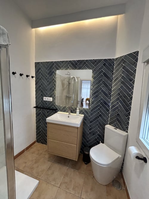 Baño moderno en el apartamento CozyHomeSevilla Judería3 de Sevilla con baldosas negras en espiga, tocador de madera, espejo y