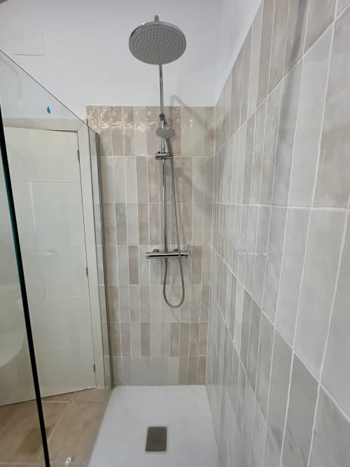 Moderno plato de ducha con alcachofa de lluvia y maneral extraíble en el baño del apartamento CozyHomeSevilla