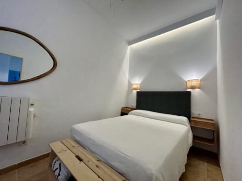 Dormitorio moderno en apartamento CozyHomeSevilla en Sevilla con cama blanca, cabecero negro e iluminación ambiental