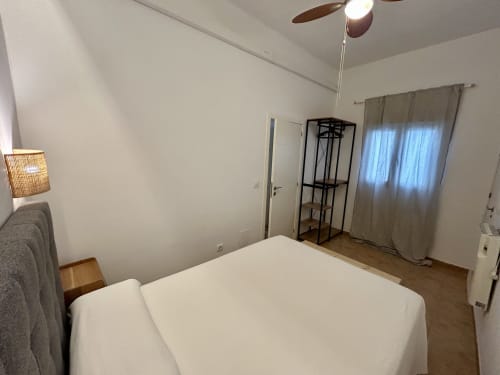 Habitación espaciosa en apartamento Judería3, Sevilla con cama blanca, ventilador de techo, estanterías y suelos de madera