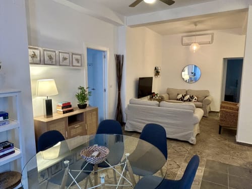Moderno apartamento de planta abierta en Sevilla con comedor, sofá beige, TV y cocina - CozyHomeSevilla Judería1
