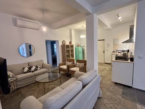 Moderna sala de estar en Sevilla con sofá, asientos, mesa redonda, cocina y planta abierta