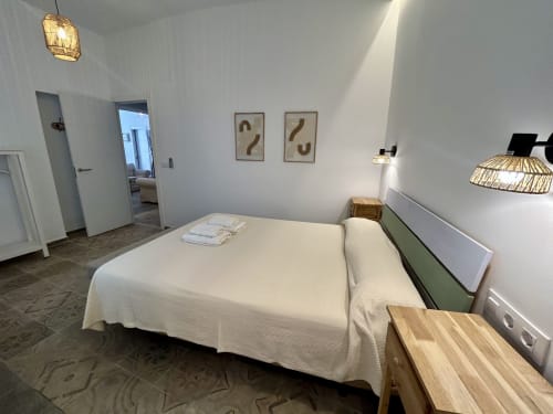 Dormitorio moderno en apartamento CozyHomeSevilla con cama blanca, muebles de madera y decoración minimalista en Sevilla