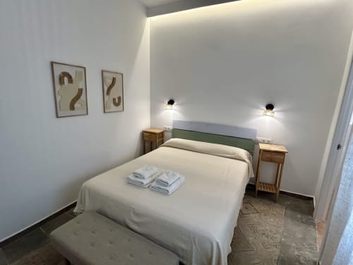 Habitación moderna en CozyHomeSevilla de Sevilla con cama queen, cabecero verde, mesitas de madera, apliques de pared y