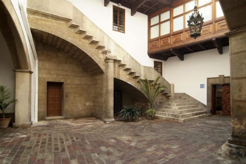 Courtyard at Casa Rural Garden Suites in Xàtiva with stone archways, wooden balcony, and brick paving