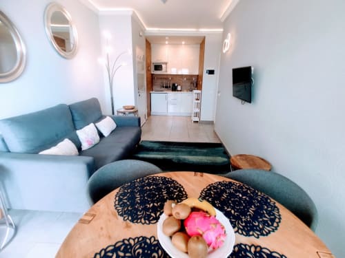 Modern apartment living area at Manage Home Tenerife with teal sofa, dining table, kitchen, and wall-mounted TV in Los