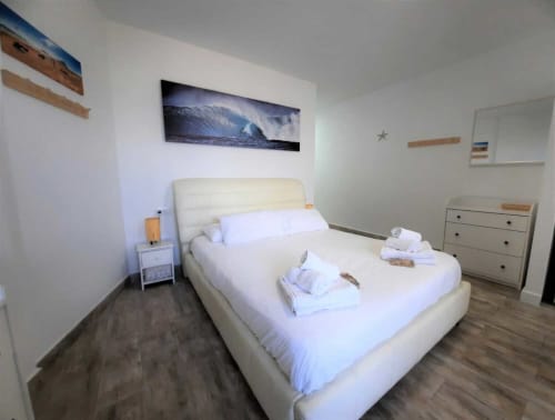 Modern bedroom at Manage Home Tenerife in Playa de las Américas with cream bed, white linens, wave artwork, and ocean-view