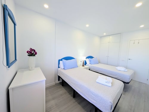 Twin bedroom at Manage Home Tenerife in Los Cristianos with blue headboards, white linens, and modern decor