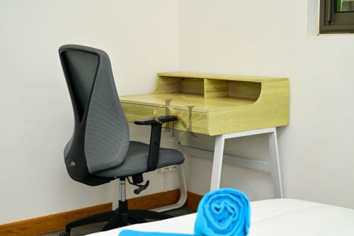 Espace de travail moderne à la villa Gerards & Angel avec bureau vert, chaise ergonomique et accessoires bleus